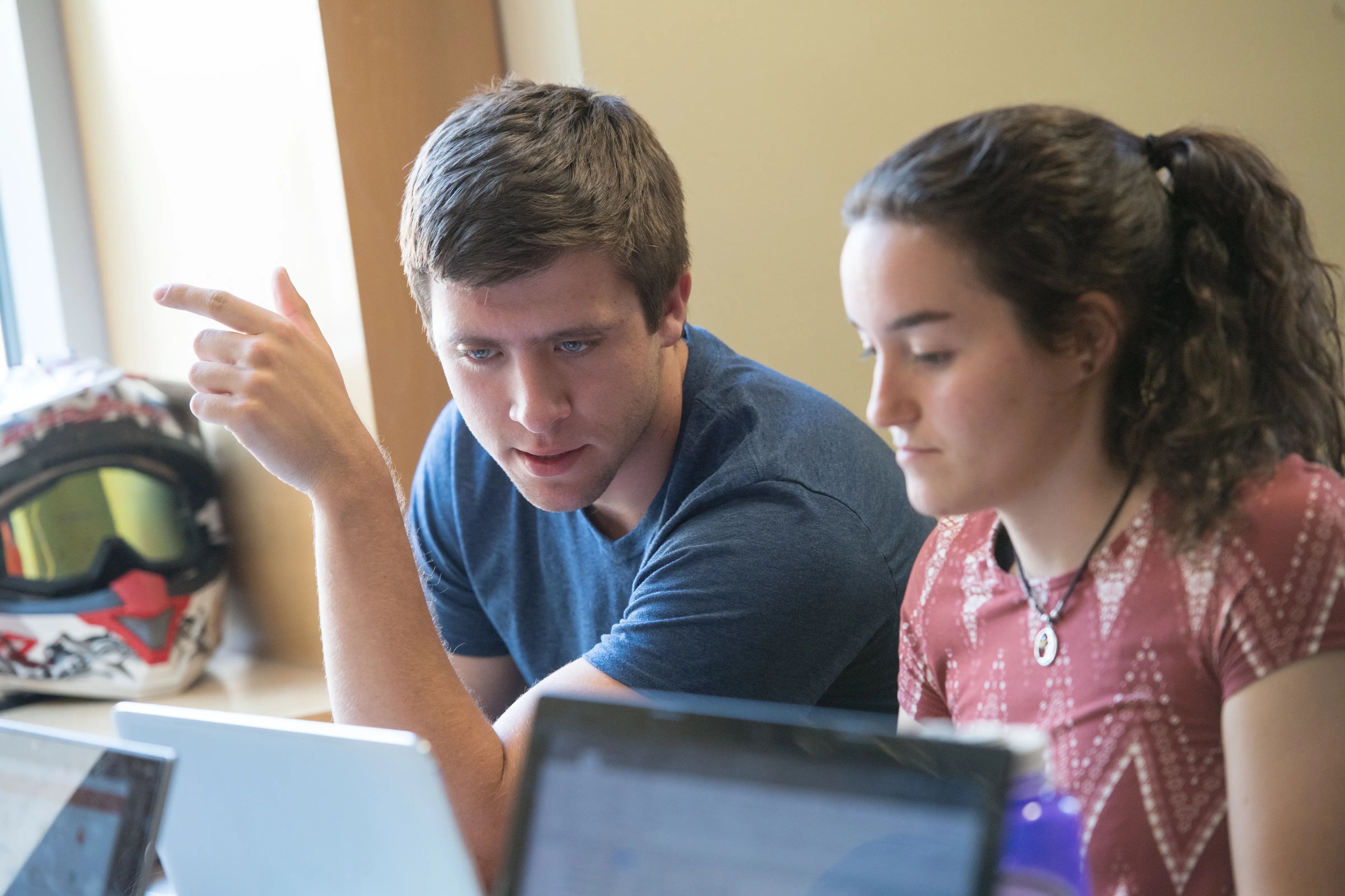Two students talking to each other solving a work problem.