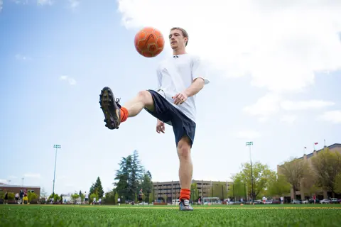 A student kicks a soccer ball around Student Legacy Park.